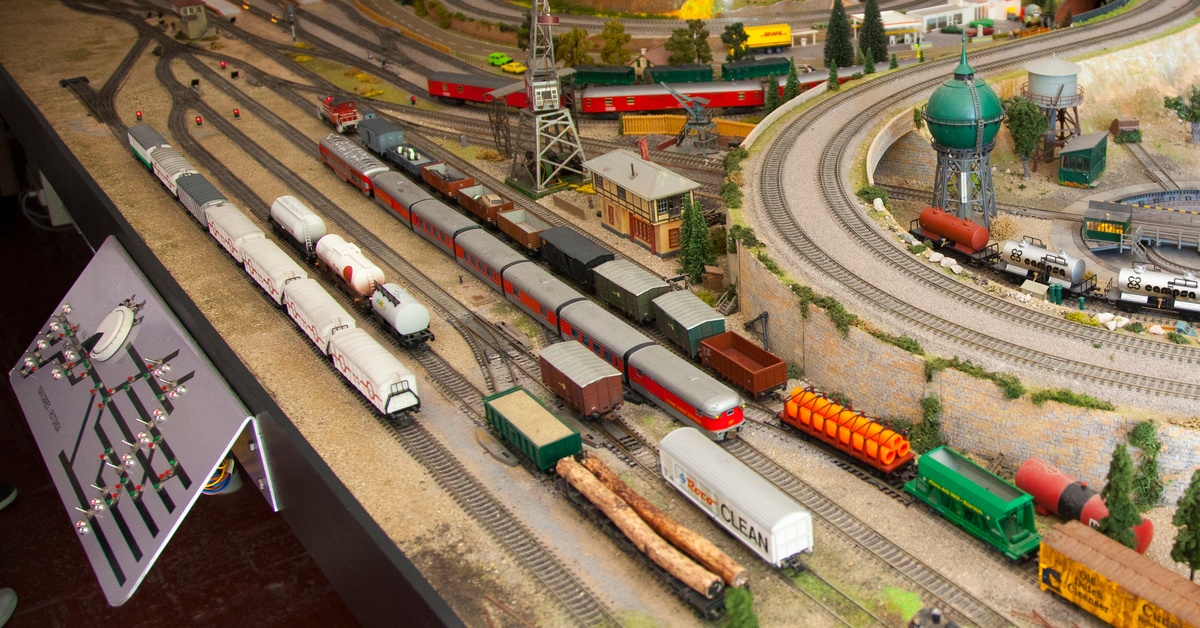 A miniature trainyard with many different tracks going in all directions. Several different trains are on the tracks.
