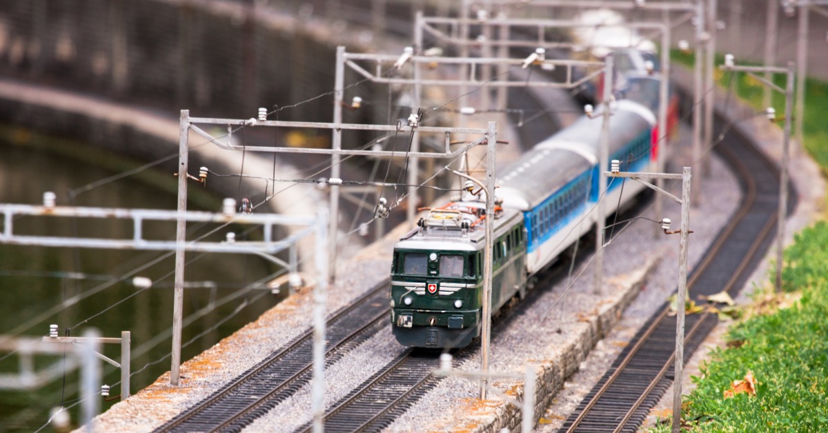 A model train on a track as part of a miniature theme park. The track is built next to a patch of fake grass.