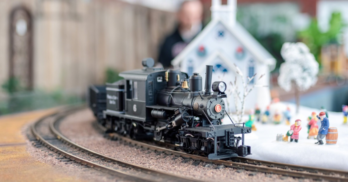A model train turning a corner on a track. There is a small Christmas scene modeled next to the track.
