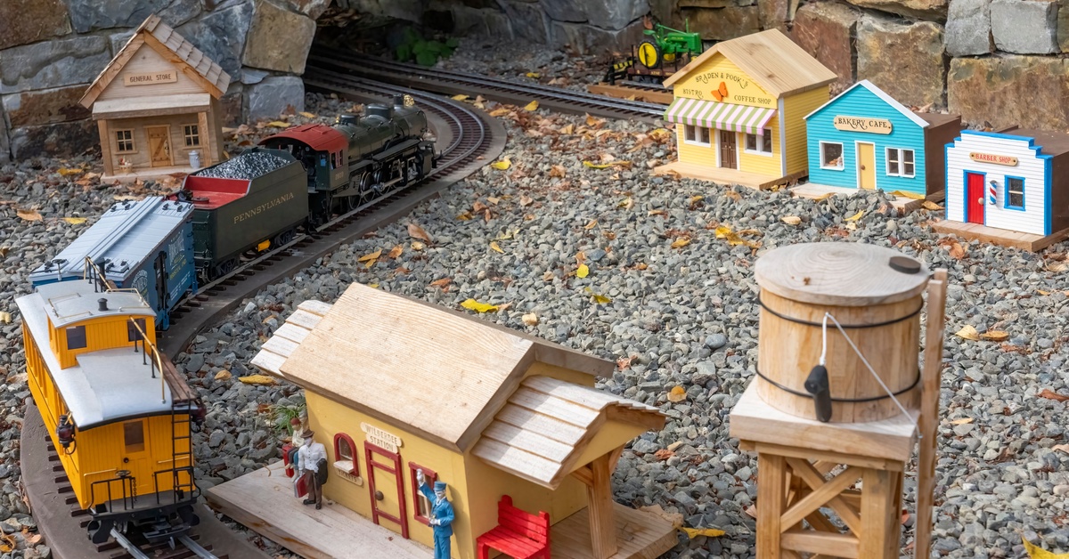 A model train set with a train about to enter a tunnel. The track is decorated with miniature buildings and a water tower.