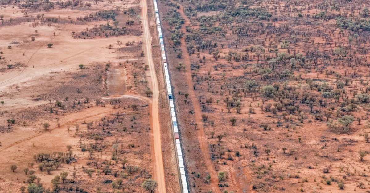 A large swath of empty, red land with a large railroad running through the middle.