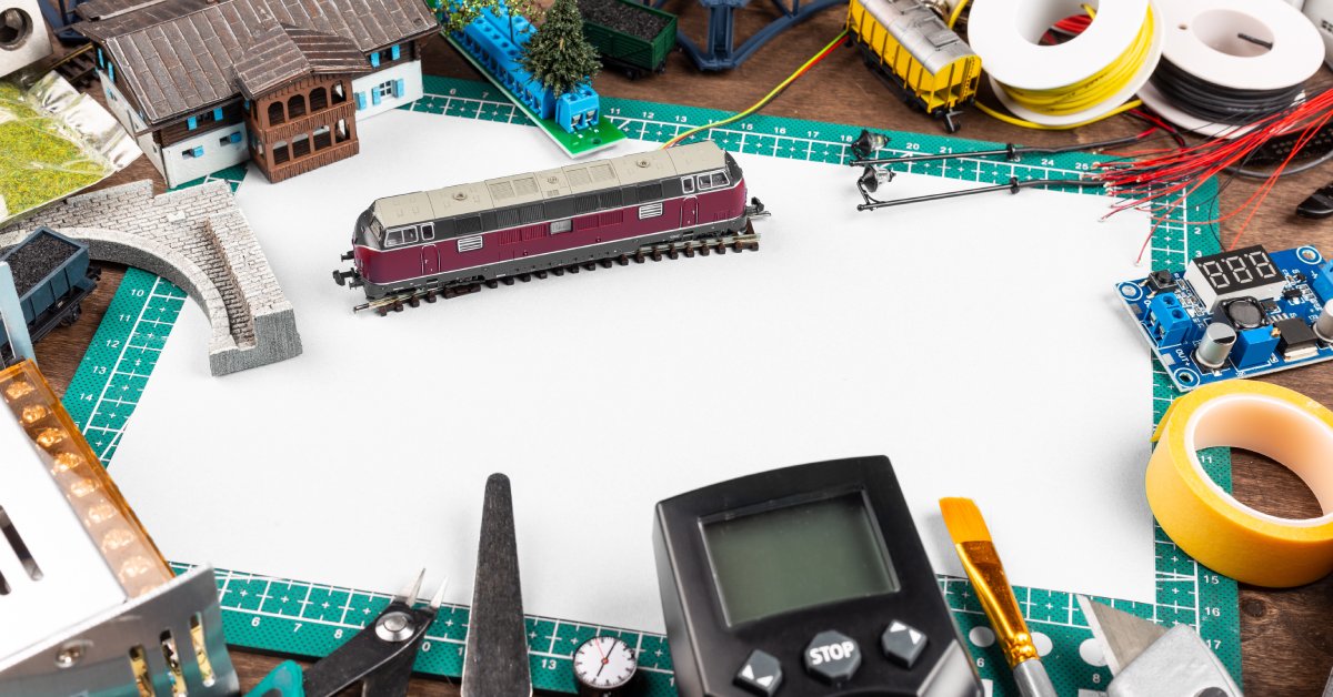 A model train car sits in the middle of a workstation, surrounded by various tools and track pieces for troubleshooting.